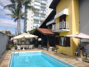 a swimming pool in front of a house with a building at Hostel Lê Castelle in Caraguatatuba
