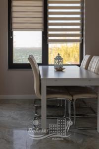 stół jadalny z białymi krzesłami i oknem w obiekcie RoApart Mamaia- Sunset Dream w Mamai