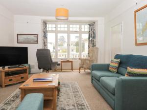 a living room with a blue couch and a tv at Clarendon House in Dawlish