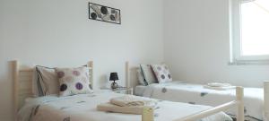 two twin beds in a room with white walls at Beach&Surf Flat in Aljezur