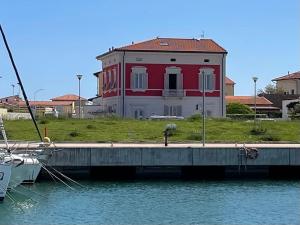 um barco ancorado numa doca com um edifício vermelho em Villino Ermione em Marina di Pisa