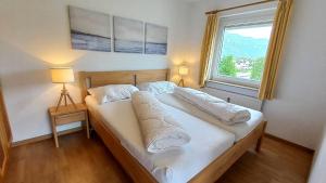 a bed in a room with a large window at KASPAR Haus KMB Seeblick Appartement am Ossiacher See mit direktem Seezugang und Hallenbad in Bodensdorf