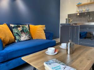 a living room with a blue couch and a wooden table at The Grosvenor Guest House in Bude