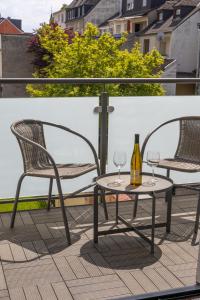 ラーンシュタインにあるLahn Living II - Modernes Apartment mit Balkonのバルコニー(椅子2脚、テーブル、ワイングラス付)