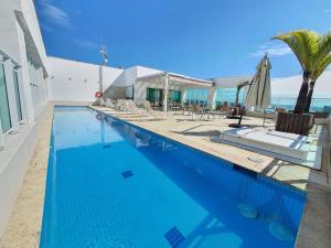 a swimming pool with chairs and an umbrella at Saint Moritz Express vista Esplanada By Rei dos Flats in Brasilia