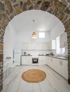 a kitchen with white cabinets and a stone wall at Salty Caves Apartments Milos in Tripiti