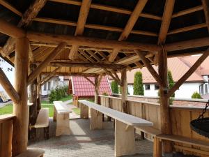 une pergola en bois avec des bancs et des tables dans l'établissement Ośrodek Wypoczynkowy EDEN Maniowy, à Maniowy