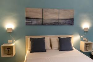 una camera da letto con un letto con tre dipinti sul muro di Blu Salina - Casa Vacanze a Margherita di Savoia
