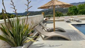 a bench with an umbrella next to a swimming pool at Georgioupoli Studio 2 with a pool and lake views in Georgioupoli