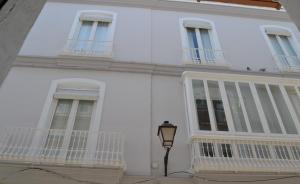 un edificio blanco con balcones y luz de la calle en APARTAMENTO LUPA en Cádiz