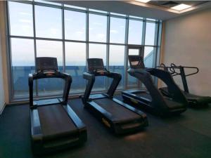 a gym with three cardio machines in front of a window at full sea view 2 bhk apartment in Ajman 