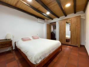 um quarto com uma cama branca e um tecto de madeira em Can ventura alojamiento entero em La Vall de Bianya