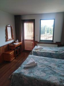 a room with two beds and a desk and a window at Вила Родопи in Dospat