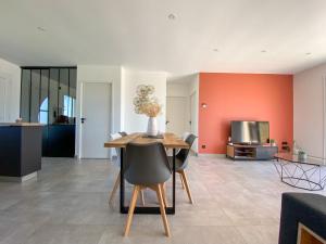 comedor con paredes de color naranja, mesa y sillas en Villa moderne , neuve piscine jacuzzi ., en Sarlat-la-Canéda