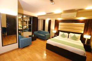 een slaapkamer met een bed en 2 stoelen in een kamer bij Hotel Palm Grand Naraina New Delhi - Couple Friendly Local IDs Accepted in New Delhi