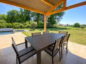 Una mesa y sillas de madera en un patio. en Villa moderne , neuve piscine jacuzzi ., en Sarlat-la-Canéda