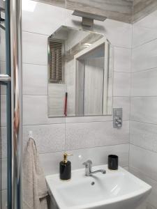 a white bathroom with a sink and a mirror at Apartament Stanley in Iława