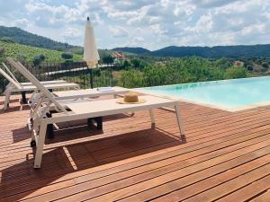 a deck with a table and chairs next to a swimming pool at Casa Nova Velha in Seixas