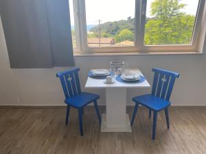 a table with two blue chairs and a white table and two windows at Villa Mara in Pula