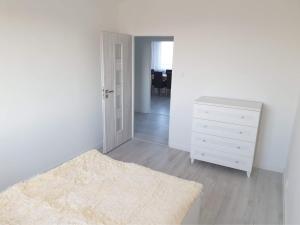 a white bedroom with a white dresser and a mirror at Apartament Stanley in Iława