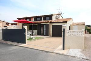 a house with a table and an umbrella on a street at Belle villa de vacances climatisée, residence TAMARIS, wifi, 2 chambres 4 à 6 couchages, accès payant pour les piscines et animations , PORTIRAGNES PLAGE LRTAMA57 in Portiragnes