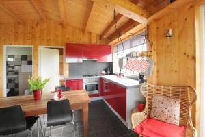 Il comprend une cuisine avec des placards rouges et un plafond en bois. dans l'établissement Chalet Egmond, à Egmond aan den Hoef