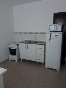 a kitchen with a stove and a sink and a refrigerator at RCM Vilas - STUDIO n 06 in Joinville