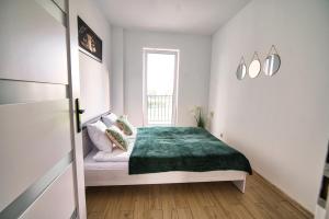 a bedroom with a bed with a green blanket at Apartament The Palm 35 by Housine in Zator