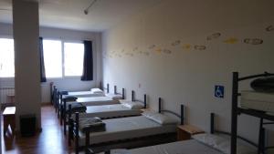 una fila de literas alineadas contra una pared en Alma del Camino - Rooms & Albergue, en Sarria