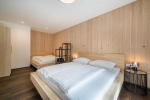 - une chambre avec un grand lit blanc et des murs en bois dans l'établissement Naturapartments Alpreid Tanne, à San Pancrazio