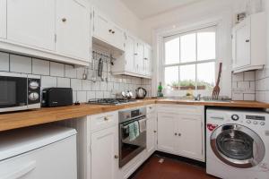 a kitchen with white cabinets and a washer and dryer at Large Shoreditch 2DBL bed loft apt in London