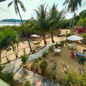 a beach with chairs and tables and palm trees at Rasta view Bangalows in Ko Chang