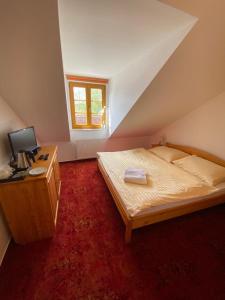 a bedroom with a bed and a desk with a computer at Pension U Kostela in Frymburk