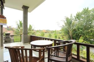 烏布的住宿－Putra Bisma Guesthouse，阳台配有桌子和两把椅子