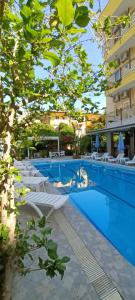 - une grande piscine avec des chaises longues blanches à côté d'un bâtiment dans l'établissement Santana Hotel, à Beldibi