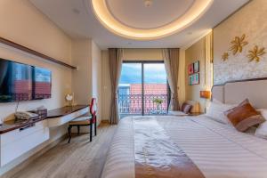 a hotel room with a bed and a desk and a window at Golden Tree Hotel & Apartment in Ho Chi Minh City