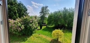 una ventana con vistas a un jardín con árboles y flores en Ferienwohnung-Haustaedter-Muehle, en Lahnau