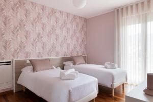 two beds in a room with pink wallpaper at B&B Monna Lisa Rooms in Montesano Scalo