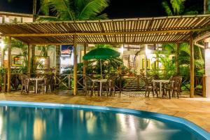 a patio with a table and chairs and an umbrella at Pousada Casarão in Boicucanga