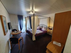 - une chambre avec un lit à baldaquin, une table dans l'établissement Hotel Jungmann, à Sarrelouis