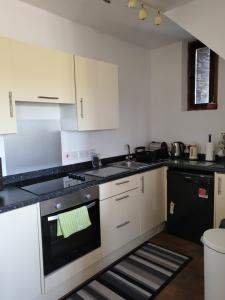 a kitchen with white cabinets and a black oven at The Hay Suite in Aberystwyth
