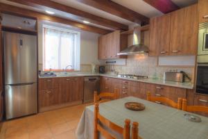 una cocina con armarios de madera y una mesa con una placa. en Villa Can Roig by Hello Homes Sitges, en Sant Pere de Ribes