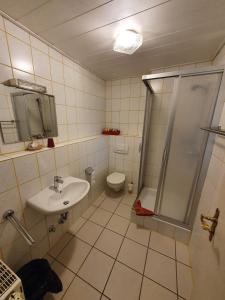 uma casa de banho com um lavatório, um chuveiro e um WC. em Hotel Jungmann em Saarlouis