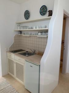 a kitchen with a sink and plates on shelves at The Seaview Lodge in Mýkonos City