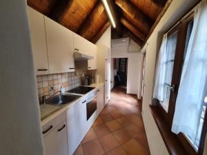 eine Küche mit weißen Schränken, einem Waschbecken und einem Fenster in der Unterkunft CASA GIOIA in Gordola