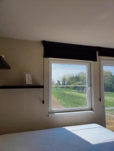 een slaapkamer met een raam met uitzicht op een veld bij Lianko - Vakantiewoning in Bekkevoort