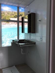 een badkamer met een wastafel en uitzicht op de oceaan bij Pousada Recanto do Arraial do Cabo in Arraial do Cabo