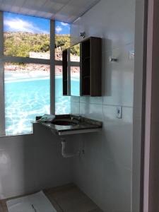 uma casa de banho com lavatório e vista para o oceano em Pousada Recanto do Arraial do Cabo em Arraial do Cabo