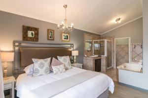 a bedroom with a bed and a tub and a sink at Overmeer Guest House in Knysna