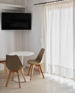 sala de estar con mesa, 2 sillas y TV en Villa Elea Apartments, en Spiliá